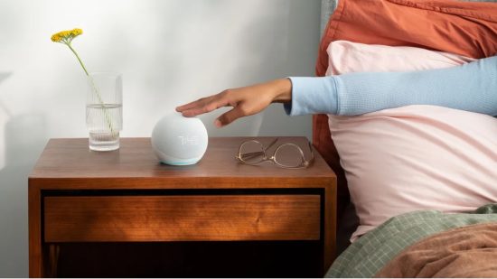 Hand pressing on an Echo Dot.