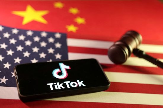 TikTok logo on phone with U.S. and China flags, next to a gavel.