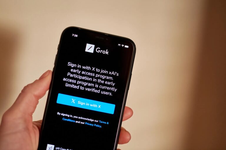 Hand holding a smartphone displaying the Grok AI early access sign-in screen.